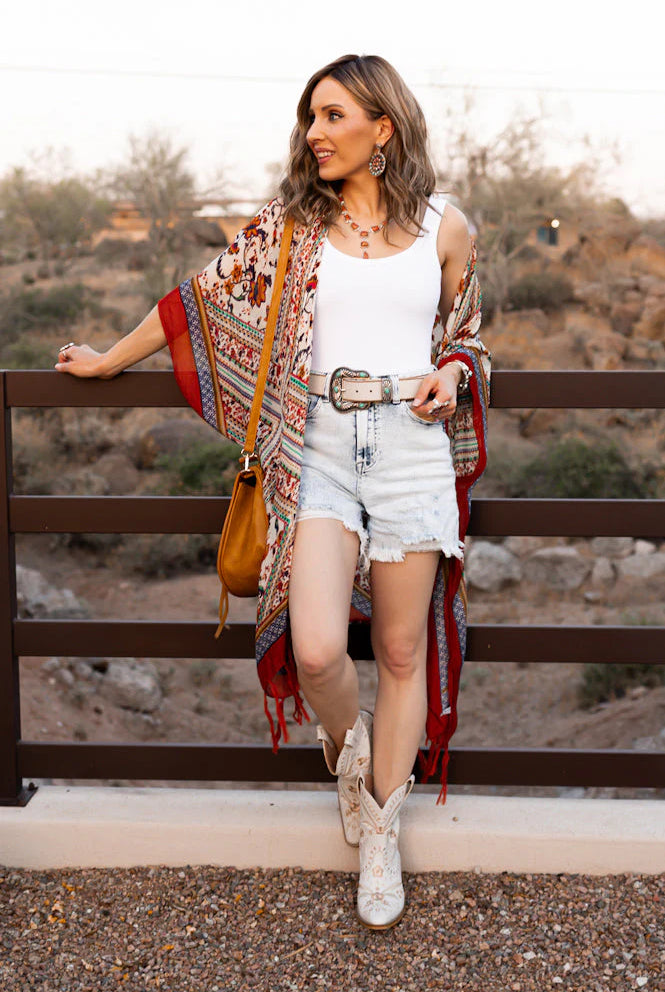 Woman in boho outfit, including kimono, shorts, and boots.